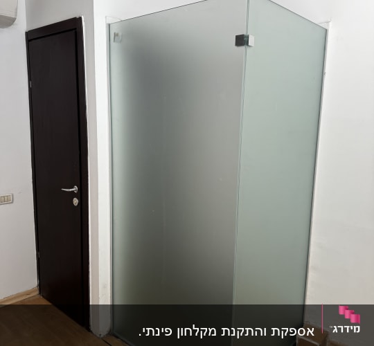 תא מקלחון זכוכית בחדר עם רצפת עץ